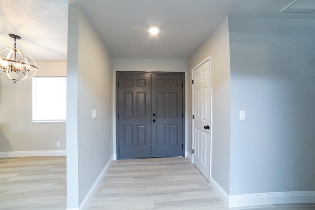 hallway featuring a notable chandelier and light hardwood / wood-style flooring