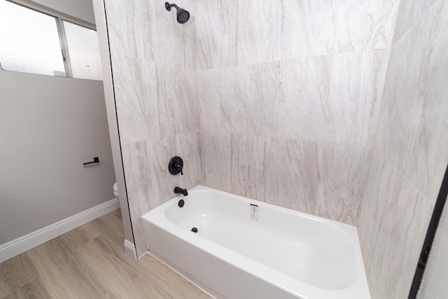 bathroom with tiled shower / bath combo, wood-type flooring, and toilet