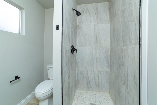 bathroom featuring a tile shower and toilet