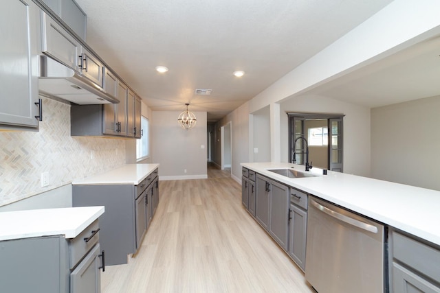 kitchen featuring stainless steel dishwasher, gray cabinets, sink, and hanging light fixtures