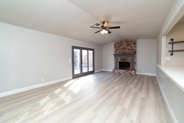 unfurnished living room featuring ceiling fan, french doors, light hardwood / wood-style flooring, lofted ceiling, and a fireplace