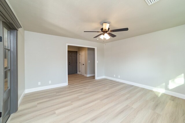 empty room featuring baseboards, ceiling fan, visible vents, and light wood-style floors