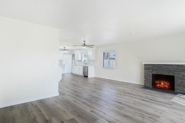 unfurnished living room featuring ceiling fan, sink, a fireplace, and light hardwood / wood-style flooring