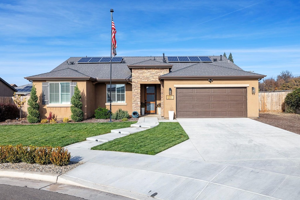 ranch-style home with solar panels, a garage, and a front lawn