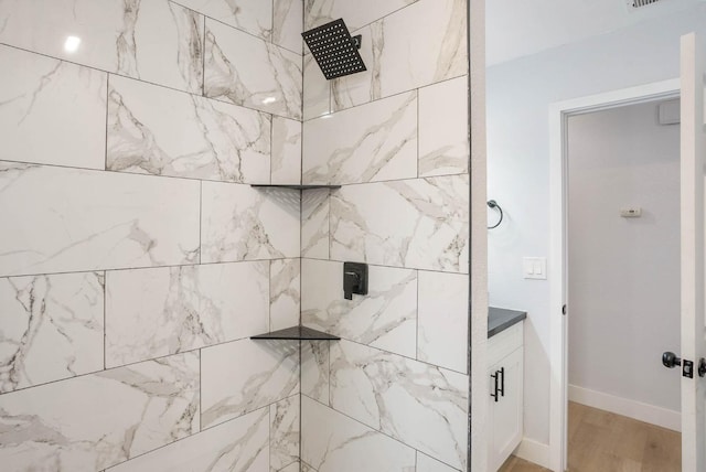 bathroom featuring vanity, a tile shower, and wood-type flooring