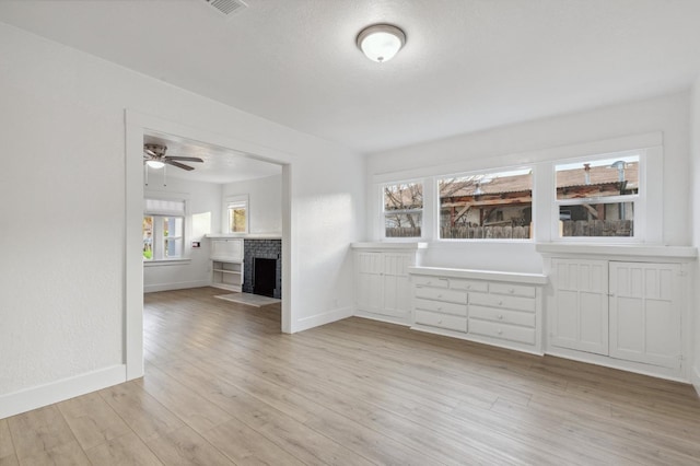 unfurnished living room featuring a fireplace, light hardwood / wood-style floors, and ceiling fan