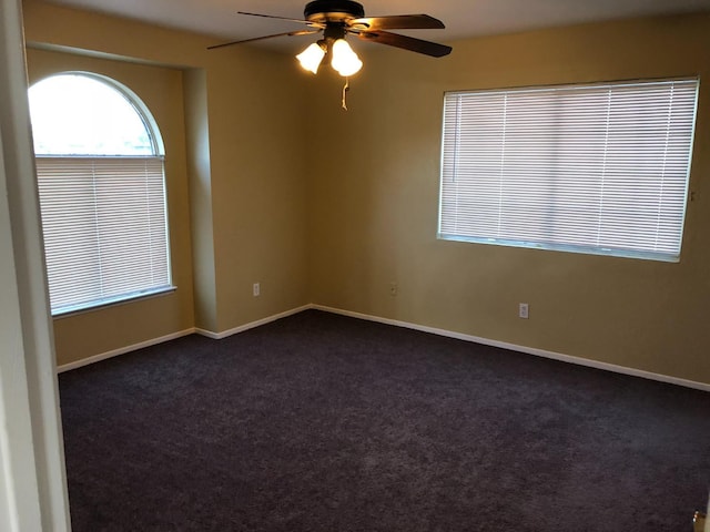 unfurnished room with dark colored carpet and ceiling fan