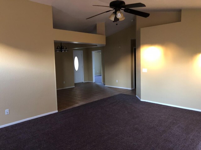 carpeted spare room featuring ceiling fan with notable chandelier and lofted ceiling