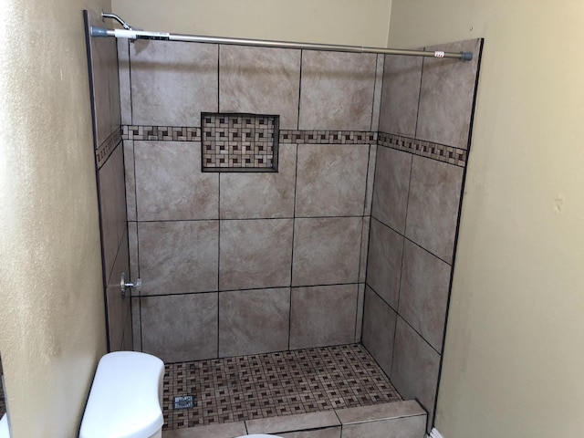 bathroom with toilet and tiled shower