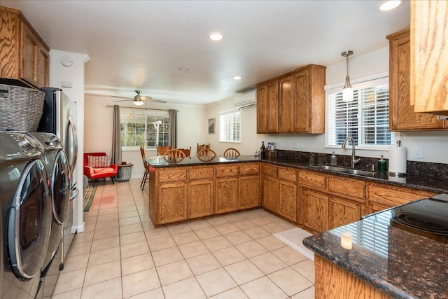 kitchen with sink, hanging light fixtures, kitchen peninsula, washer and clothes dryer, and light tile patterned floors