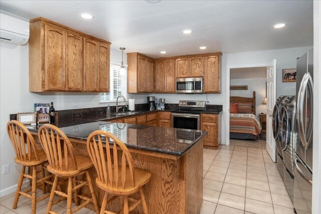 kitchen featuring a breakfast bar, sink, washing machine and dryer, appliances with stainless steel finishes, and decorative light fixtures