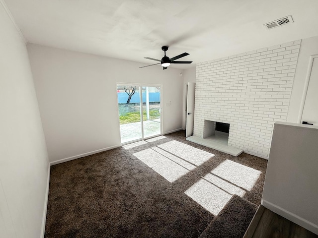 unfurnished living room featuring a brick fireplace, ceiling fan, and dark colored carpet