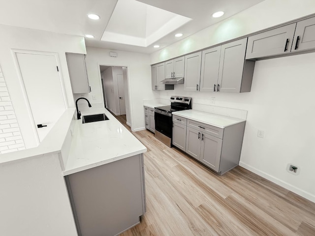 kitchen with light stone counters, a raised ceiling, sink, gray cabinets, and stainless steel electric range oven