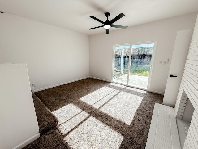 unfurnished living room with ceiling fan, dark carpet, a water view, and a fireplace