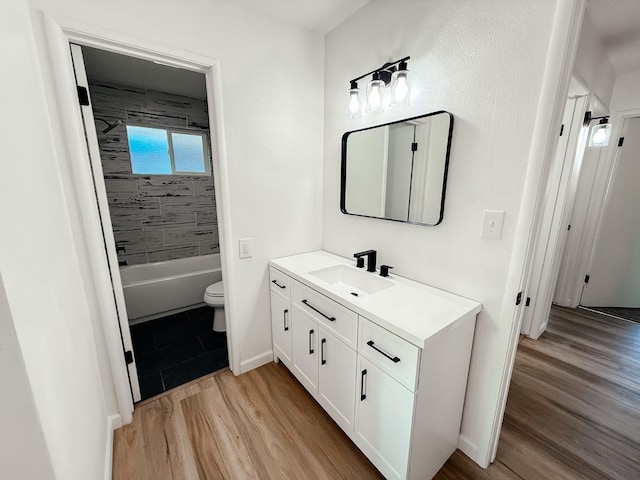 full bathroom featuring vanity, hardwood / wood-style flooring, toilet, and tiled shower / bath