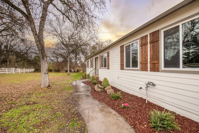 property exterior at dusk with a lawn