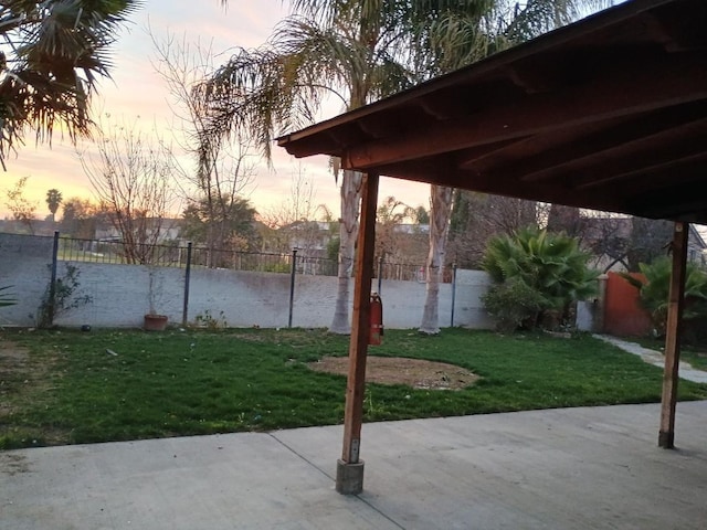 patio terrace at dusk featuring a lawn