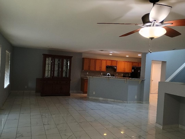 kitchen with kitchen peninsula, backsplash, a breakfast bar, ceiling fan, and fridge