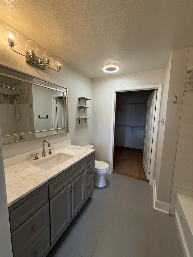 bathroom with toilet, vanity, a textured ceiling, and walk in shower