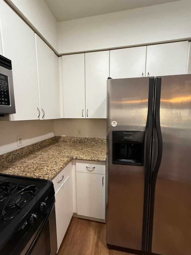 kitchen with white cabinetry, light stone counters, dark hardwood / wood-style flooring, and appliances with stainless steel finishes