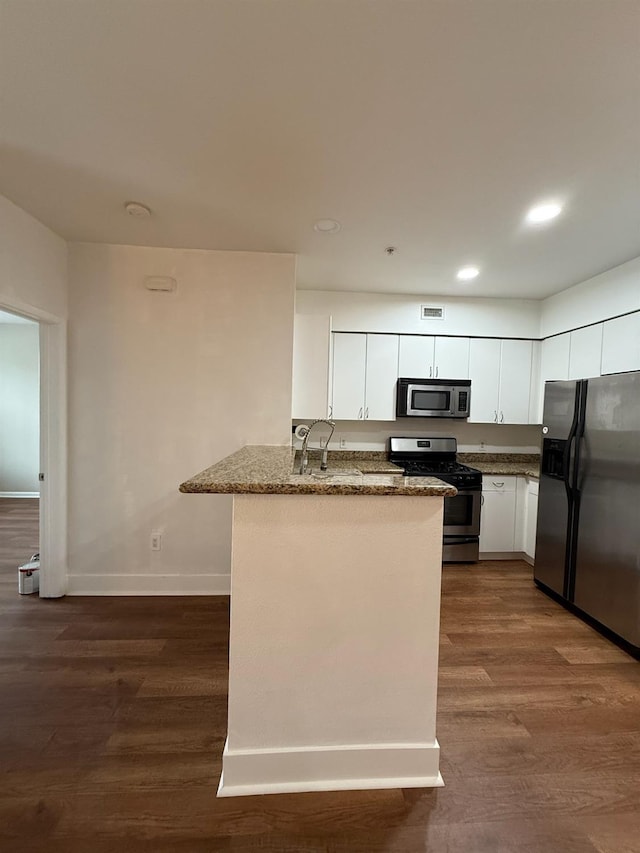 kitchen featuring kitchen peninsula, dark stone countertops, white cabinetry, and stainless steel appliances