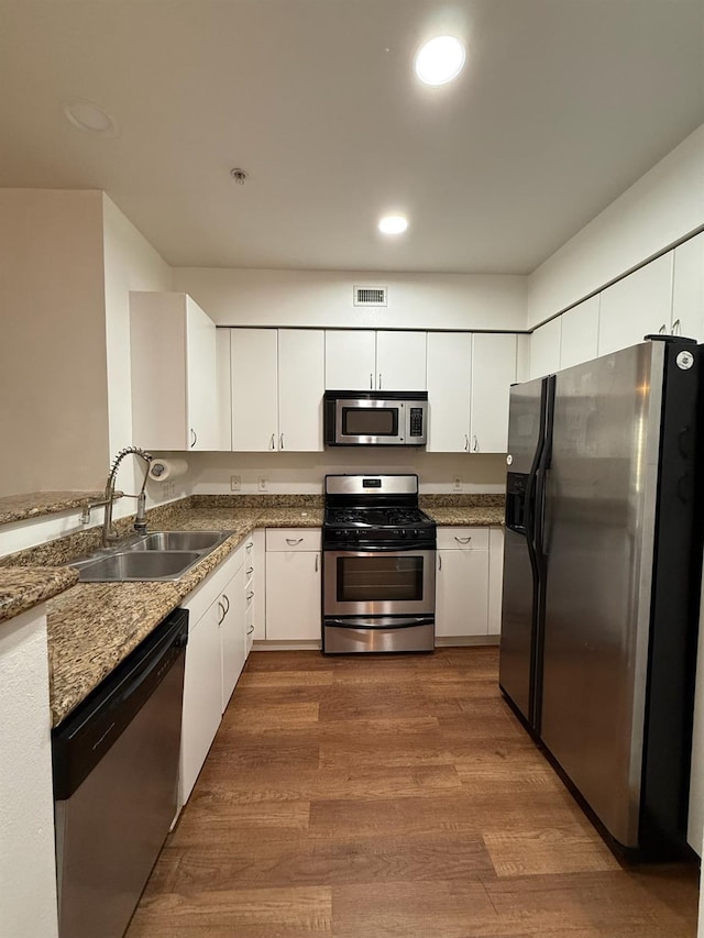 kitchen with white cabinets, sink, stainless steel appliances, and hardwood / wood-style floors