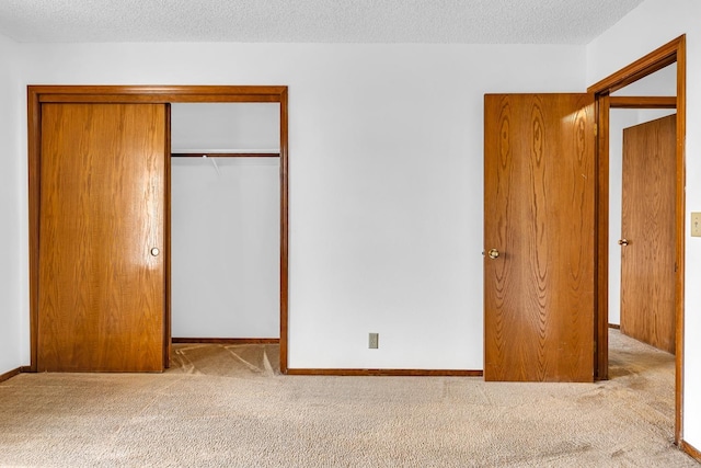 unfurnished bedroom featuring a textured ceiling, light colored carpet, and a closet