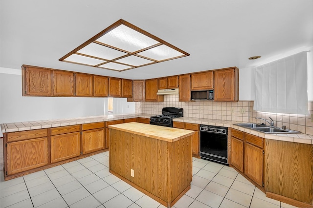 kitchen featuring sink, light tile patterned floors, a center island, and black appliances