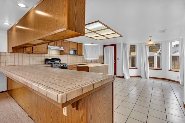 kitchen featuring kitchen peninsula, tasteful backsplash, black appliances, tile counters, and light tile patterned flooring