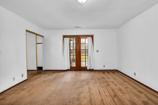 carpeted empty room featuring french doors and a textured ceiling