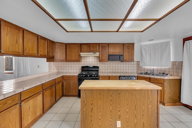 kitchen featuring a center island, sink, wood counters, light tile patterned floors, and black appliances