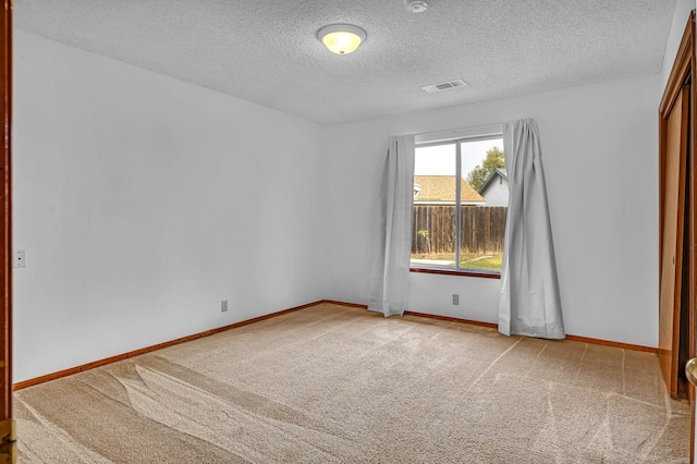 unfurnished room featuring a textured ceiling and light carpet