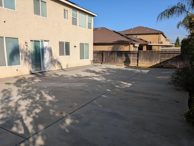 rear view of house with a patio area, fence, and stucco siding