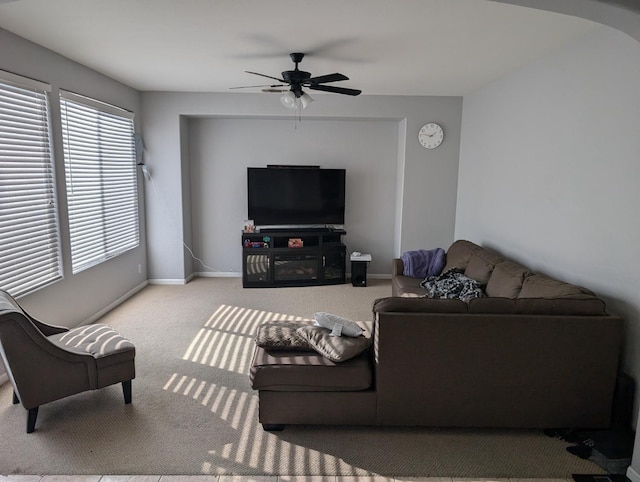 living area featuring light carpet, a ceiling fan, and baseboards