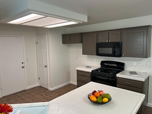 kitchen with gray cabinetry, backsplash, tile counters, and black appliances