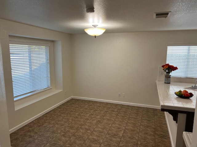 unfurnished dining area featuring plenty of natural light and a textured ceiling