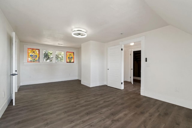 spare room with lofted ceiling and dark wood-type flooring