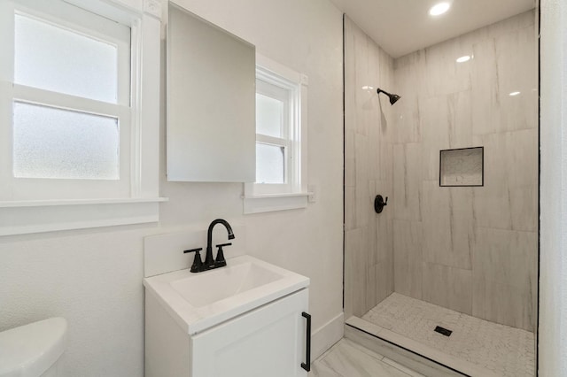 bathroom with vanity, toilet, and a tile shower