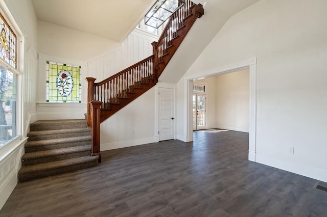 staircase with wood-type flooring and high vaulted ceiling