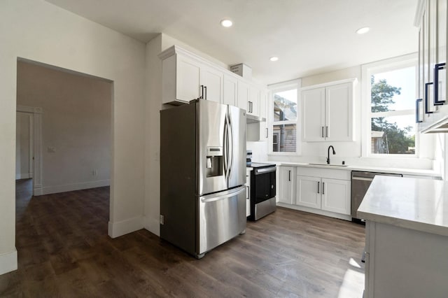 kitchen with appliances with stainless steel finishes, dark hardwood / wood-style floors, white cabinetry, and sink