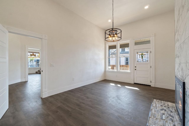 entryway with a fireplace, dark hardwood / wood-style floors, a healthy amount of sunlight, and a notable chandelier