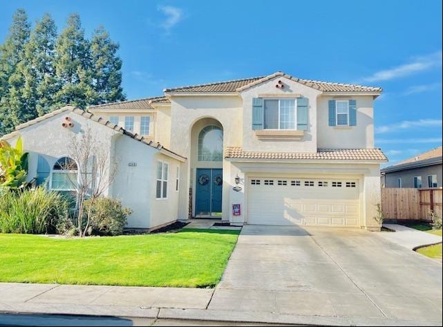 mediterranean / spanish home with a garage and a front lawn