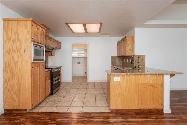 kitchen with appliances with stainless steel finishes, kitchen peninsula, sink, and backsplash