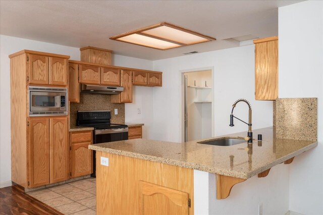 kitchen with stainless steel microwave, sink, black electric range oven, and kitchen peninsula