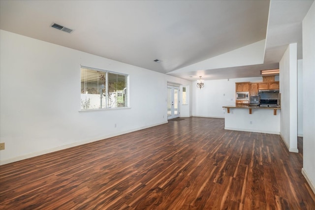 unfurnished living room featuring an inviting chandelier, dark hardwood / wood-style flooring, and vaulted ceiling