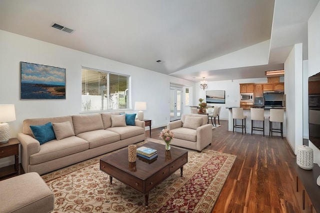 living room featuring a wealth of natural light, vaulted ceiling, and dark wood-type flooring