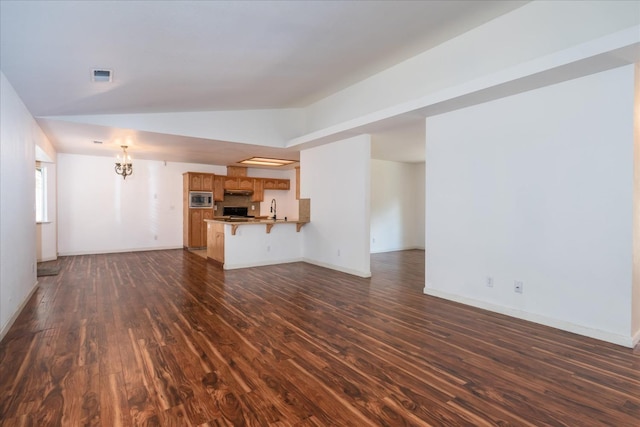 unfurnished living room with dark wood-type flooring, lofted ceiling, an inviting chandelier, and sink