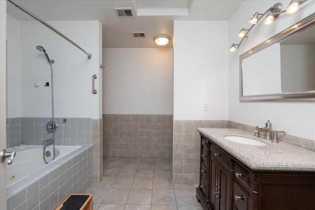 bathroom featuring vanity, tile patterned floors, tiled bath, and tile walls