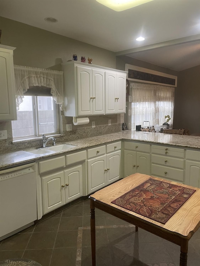 kitchen with dark tile patterned floors, white cabinets, dishwasher, and sink