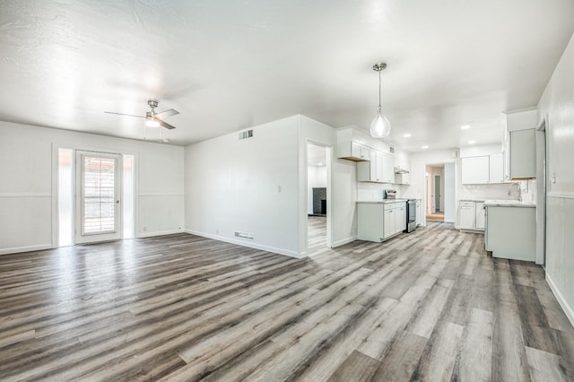 unfurnished living room featuring ceiling fan and light wood-type flooring